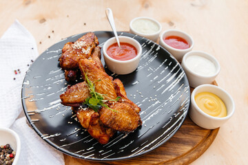 appetizing chicken wings in a plate. many sauces near the plate