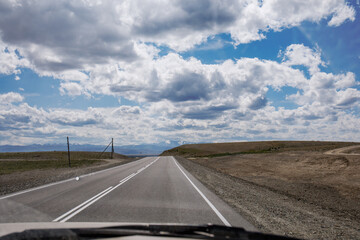 Asphalt road to the horizon through the windshield of a car. Travel in the Altai Republic in summer. 