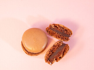 Sweet chocolate macarons, on a pink background.