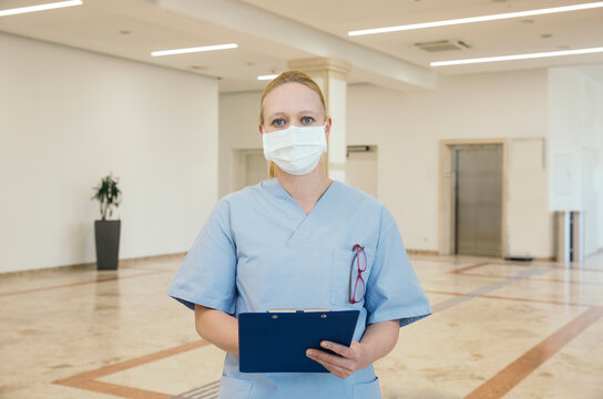 Austria, Vienna, Portrait of nurse in face mask holding clipboard in hospital