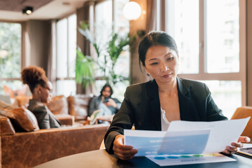 Italy, Businesswoman looking at documents at table in creative studio