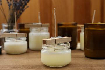 Glass jars with wax on wooden table. Handmade candles