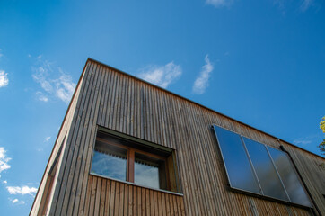 Solar collectors perpendicular to the wooden facade in front of a blue sky