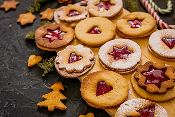 Homemade Christmas cookies with raspberry jam. Traditional Linzer cookies on a dark table, copy space
