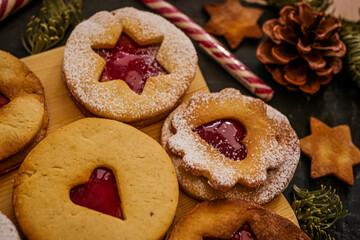 Naklejka premium Homemade Christmas cookies with raspberry jam. Traditional Linzer cookies on a dark table, copy space