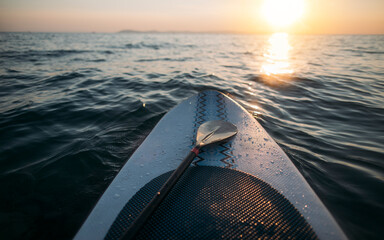 Paddleboard with paddle on sunset sea