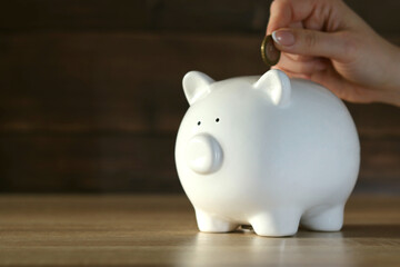 The girl throws coins into a piggy bank in the form of a ceramic piggy bank