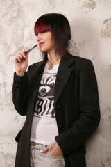 Black and red haired girl with a vape in the coat and white t-shirt