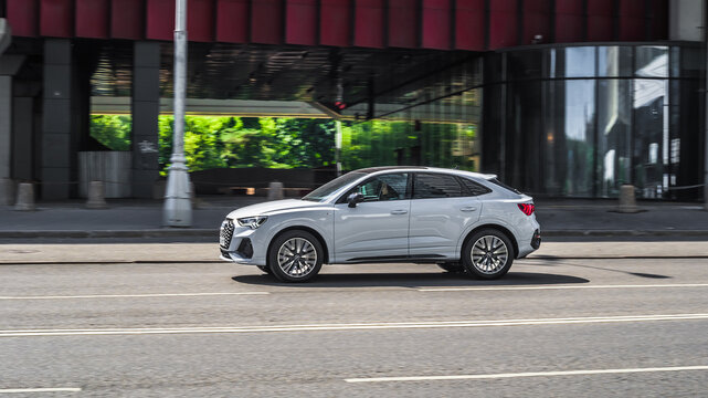 Side view rolling shot with Audi Q3 Sportback car in motion. Second generation crossover driving along the street in city with blurred background