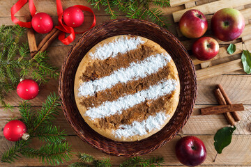 Round homemade cinnamon apple pie in a wicker plate on a wooden table with Christmas decorations...