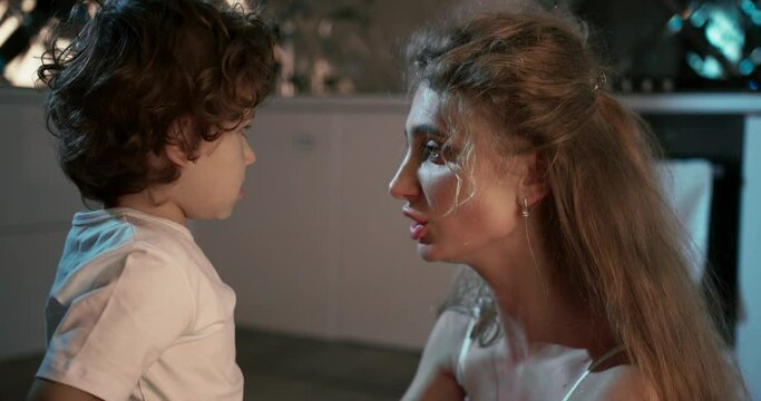 Close-up view of a mother shouting at her son whilst seated on the kitchen floor. Maternal tenderness.