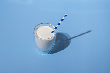 World Milk Day. Glass of milk with a straw against blue background. Sample. Package.