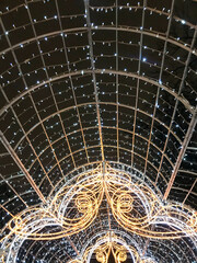 Stylish New Year decorations and arch with garlands and two silhouettes. Christmas tree decorated with garlands and red ribbon. Christmas festive decor and illumination in winter holidays