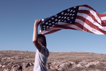 A boy holding waving US flag, beeng a patriot concept