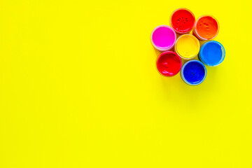 A bright circle similar to a flower made up of cans of paint on a yellow background with a place for text. top view, flat lay, copy space, isolate