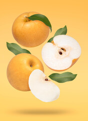 Fresh Snow pear with green leaves falling in the air isolated on yellow background, Korean pear fruit on yellow background With clipping path.
