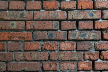 Weathered dark brick background. Close-up view of old molded red brick wall covered with cracks and scratches. Copy space for your text and decorations. Demolition theme.