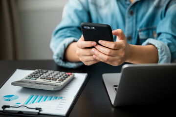 close up of young women using smartphone and laptop computer working business report analytic at home, accounting document, marketing and financial business concept.