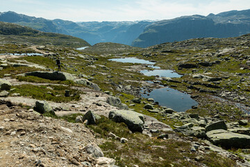 A woman stands on the rock on the hiking trail to Trolltunga, Vestland county, Norway