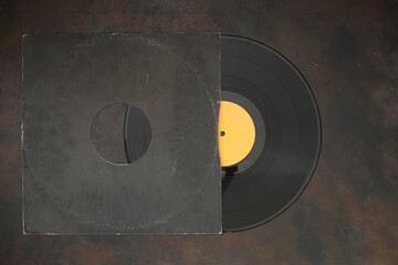 Aged black paper cover and vinyl LP record isolated on rusty background