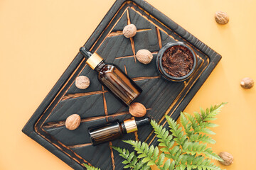Bottles of nutmeg essential oil with scrub on color background
