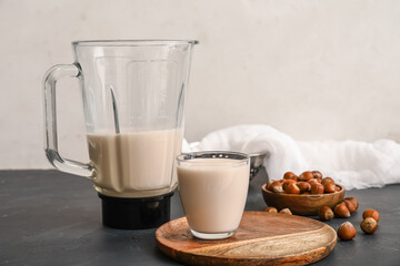 Wooden board with tasty hazelnut milk and ingredients on kitchen table