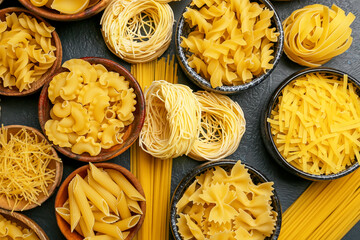 Different types of uncooked pasta on dark background
