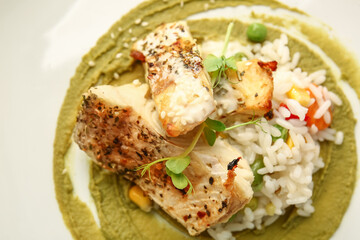 Plate with tasty baked cod fillet, rice and guacamole sauce, closeup