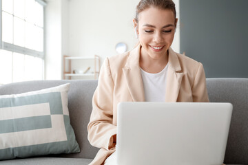 Young woman with laptop video chatting at home