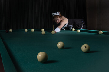 Young sexy chambermaid plays billiard. Pin up style.