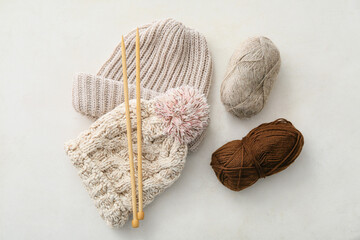 Fototapeta na wymiar Warm hats, knitting yarn and needles on light background