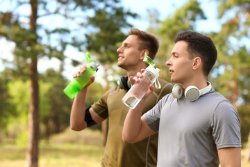 Sporty young men drinking water in park