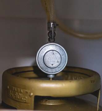 Gás de cozinha. Foto de um botijão de gás de cozinha ligado a um regulador de gás. GLP, butano, propano.