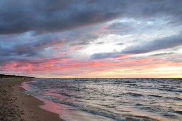 Panoramic view from the Baltic sea shore at sunset. Dramatic storm sky, glowing clouds, golden...