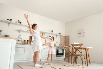 Young woman and her little daughter dancing in kitchen