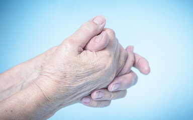 Fototapeta premium Application of antibacterial gel with transparent in old woman hands. Isolated light blue background. 