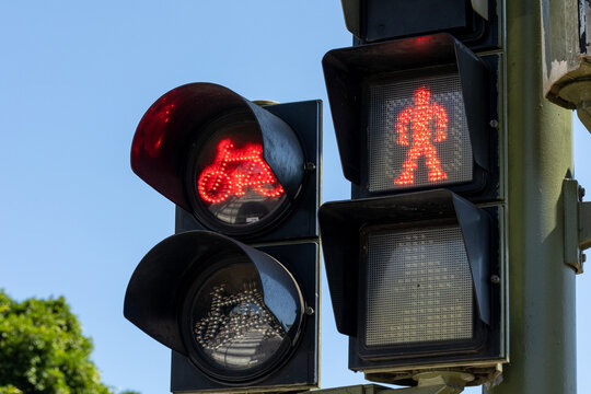 Red traffic lights of bicycles and pedestrians against a blue sky on a pole on the street