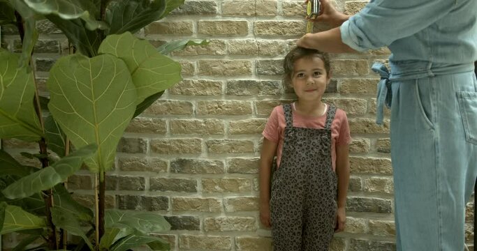 Mixed race mother measuring daughter&rsquo;s height