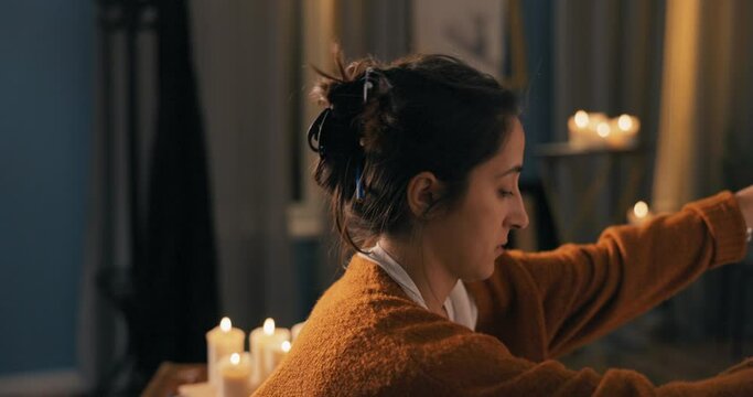 Beautiful hard-working girl sits in painting studio, gets down to finish work, takes out sketch of tree, branches, nature from painting folder places it on easel attaches it begins to shade elements