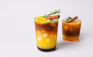 Glasses of tasty coffee with orange juice on light background