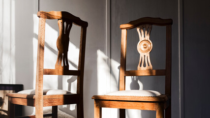Close-up of a pair of oak dining chairs  under sunlight isolated in a cozy and stylish room 