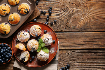 Composition with tasty blueberry muffins and berries on wooden background, closeup