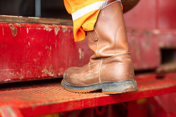 Action of a industrial worker with full PPE, safety shoe and coverall suit is walking up on anti-slip metal stair step. Close-up and selective focus.