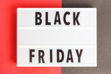 Inscription Black friday on a lightbox on black and red background top view.
