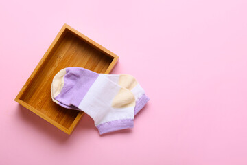 Wooden box with socks on pink background