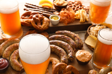Glasses of cold beer, board with Bavarian sausages and snacks on table, closeup. Oktoberfest...