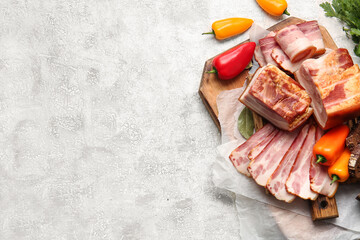 Wooden board with tasty smoked bacon and fresh vegetables on light background, closeup