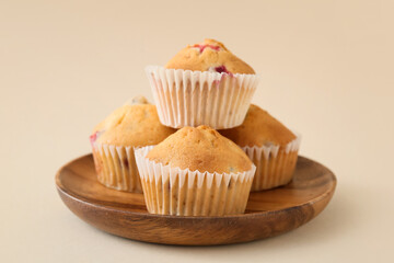 Plate with tasty cranberry muffins on color background