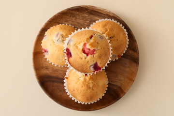 Plate with tasty cranberry muffins on color background