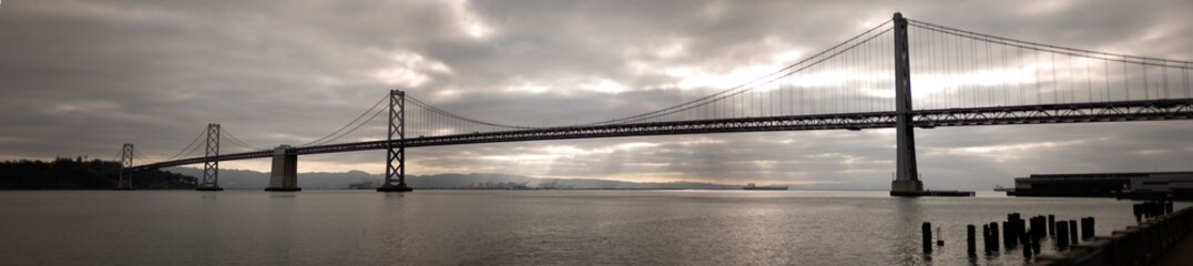 Panoramic view of the San Francisco Bay bridge with rays of sun in the background